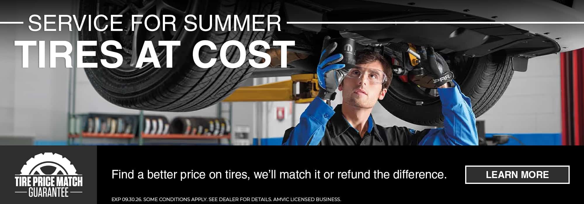 Mechanic working on a car tire with "Service for Summer, Tires at Cost" promotion banner.