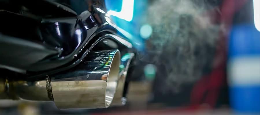 Close-up of car exhaust pipe emitting smoke, highlighting vehicle emissions.