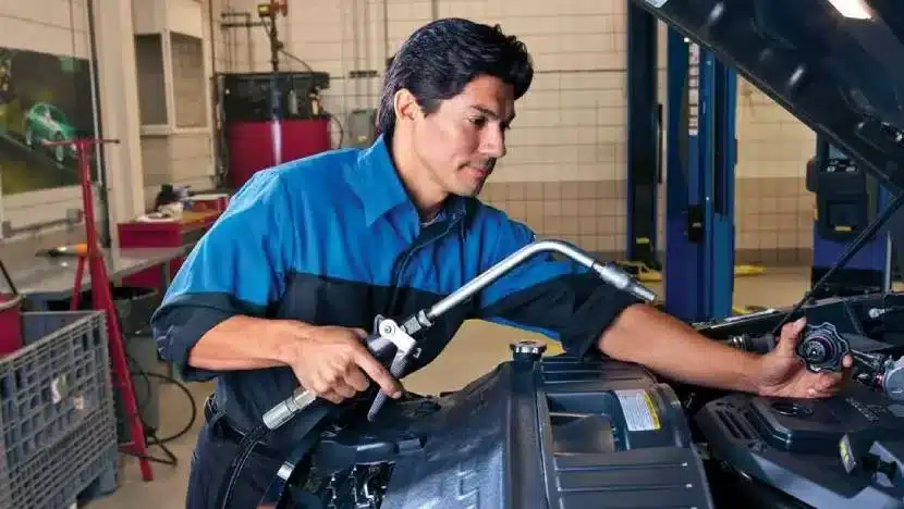 Mechanic refilling vehicle's cooling system in auto repair shop.