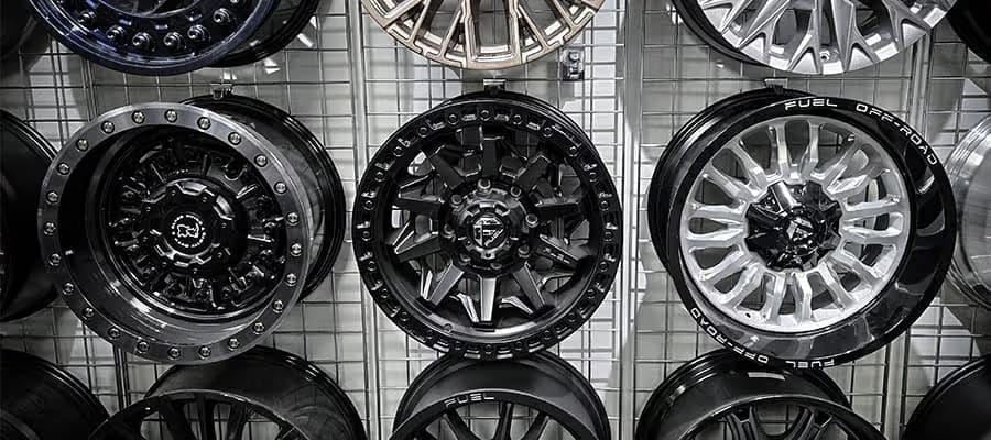 Display of various off-road alloy wheels on a grid wall, featuring black and silver designs.
