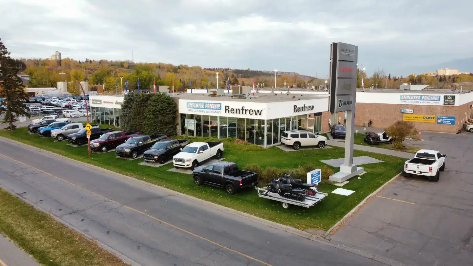 Car dealership exterior featuring Chrysler, Dodge, Jeep, and Ram vehicles at sunset.