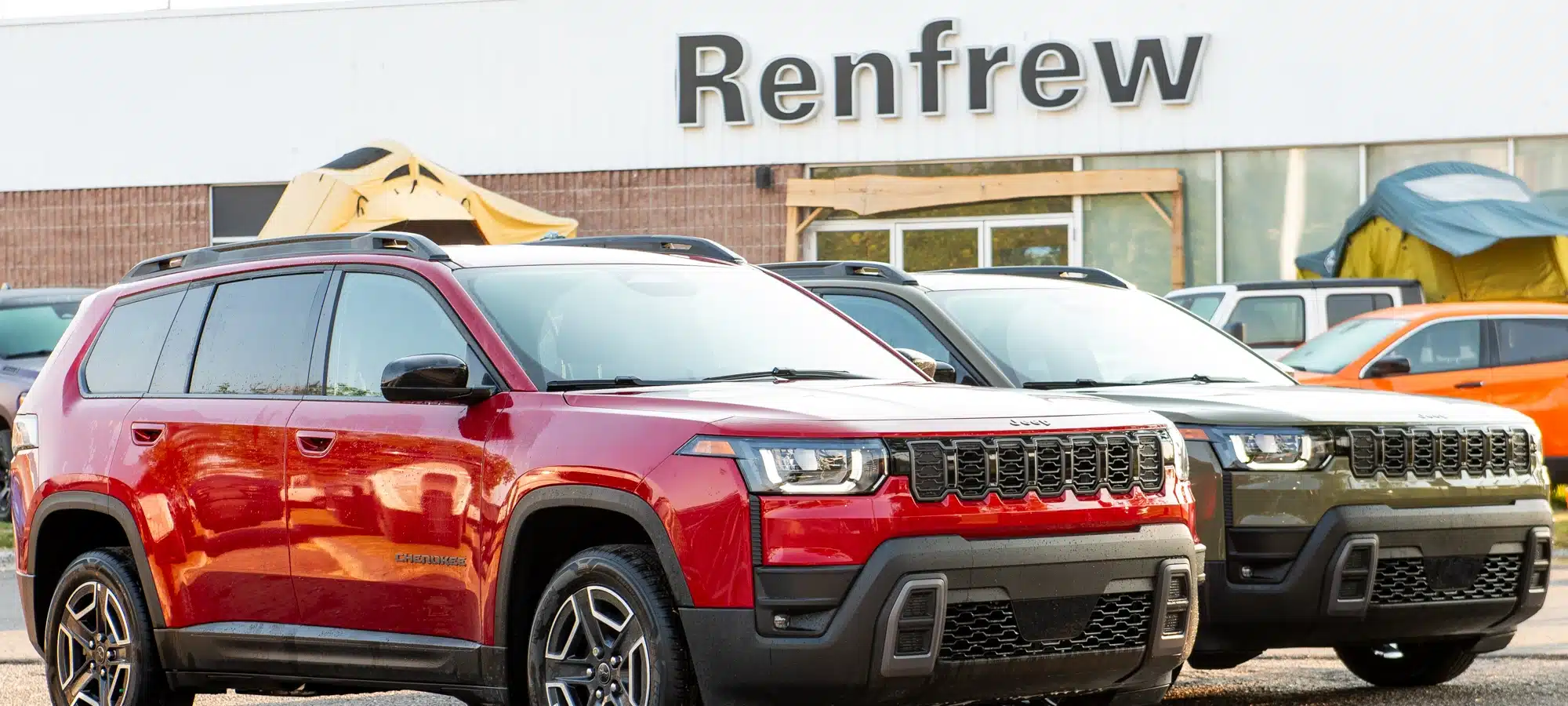 Red and gray SUVs parked in front of a Renfrew dealership building.
